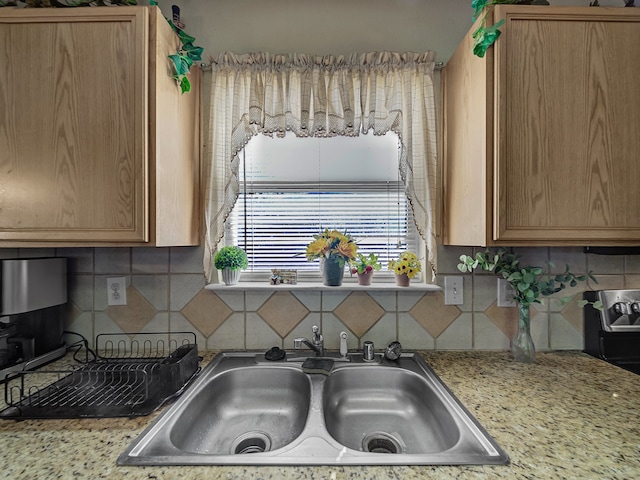 kitchen featuring decorative backsplash, sink, and light stone countertops