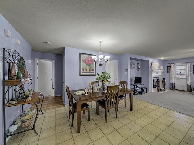 dining room with a textured ceiling, light colored carpet, and an inviting chandelier