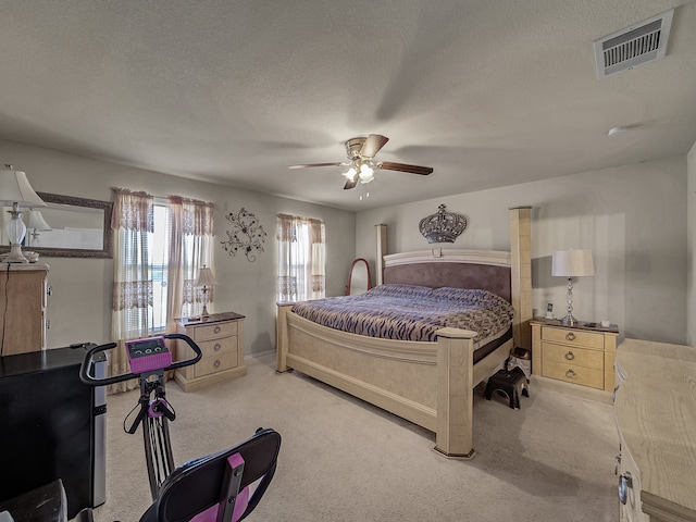 carpeted bedroom featuring ceiling fan and a textured ceiling