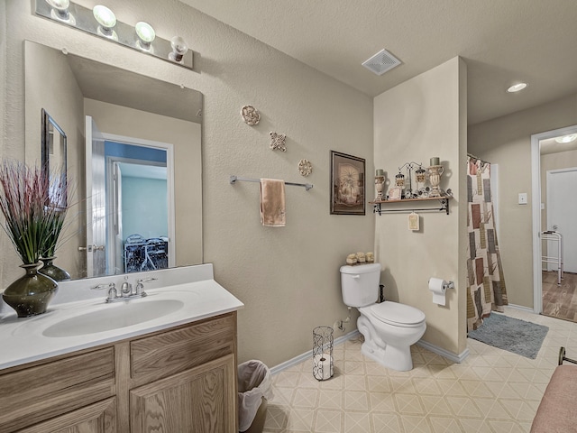 bathroom with tile patterned flooring, vanity, a textured ceiling, and toilet