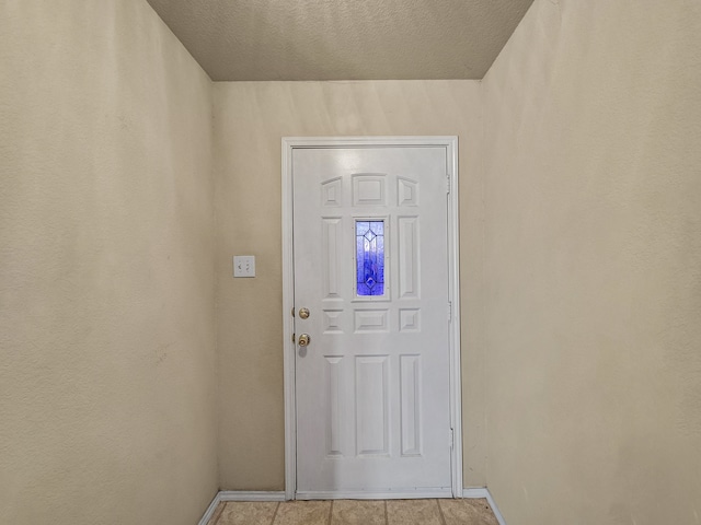 doorway to outside with light tile patterned floors and a textured ceiling