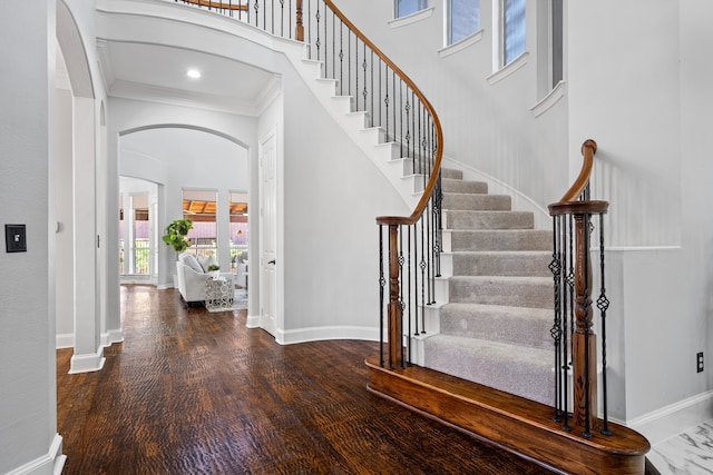 entryway featuring dark hardwood / wood-style floors, crown molding, and a high ceiling