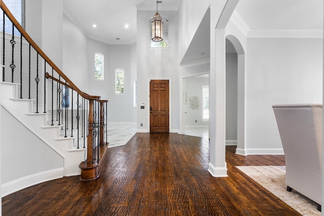 entrance foyer featuring hardwood / wood-style floors, ornamental molding, and a high ceiling