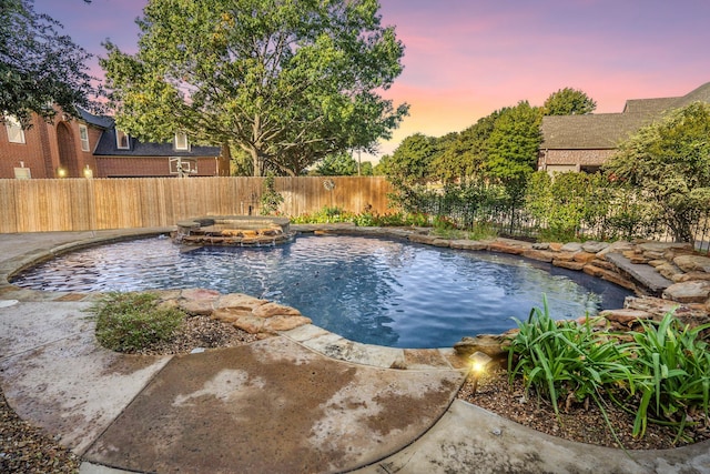 pool at dusk with an in ground hot tub