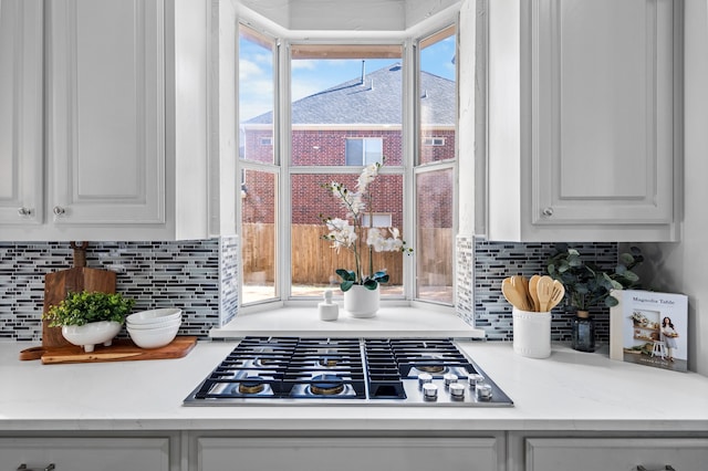 details with white cabinets, light stone counters, backsplash, and stainless steel gas cooktop