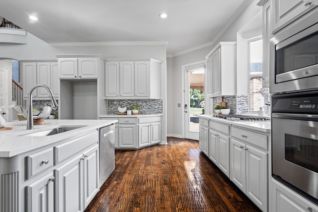 kitchen featuring sink, dark hardwood / wood-style flooring, decorative backsplash, white cabinets, and appliances with stainless steel finishes