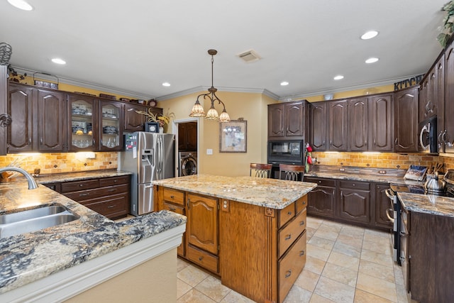 kitchen featuring dark brown cabinetry, sink, washer / clothes dryer, pendant lighting, and appliances with stainless steel finishes