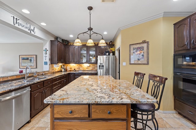 kitchen with black appliances, a kitchen breakfast bar, a kitchen island, and sink