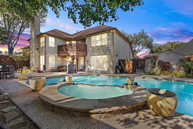 pool at dusk with an in ground hot tub