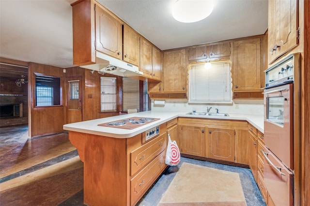 kitchen featuring kitchen peninsula, stainless steel double oven, ceiling fan, sink, and white electric cooktop