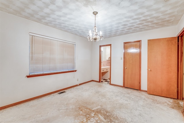 unfurnished bedroom featuring a notable chandelier, a textured ceiling, and connected bathroom