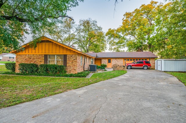 ranch-style house with a front yard, central AC unit, and a storage unit