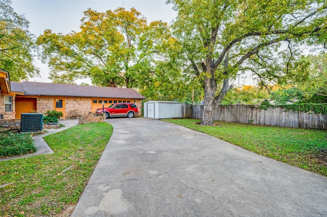 view of front of home featuring a front lawn, central AC unit, and a storage unit