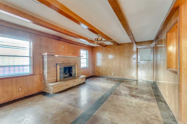 unfurnished living room with ceiling fan, beam ceiling, and wooden walls