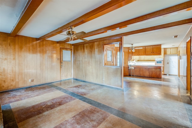 unfurnished room with beamed ceiling, ceiling fan, and wooden walls