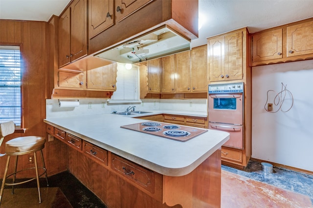 kitchen featuring electric cooktop, oven, kitchen peninsula, and sink