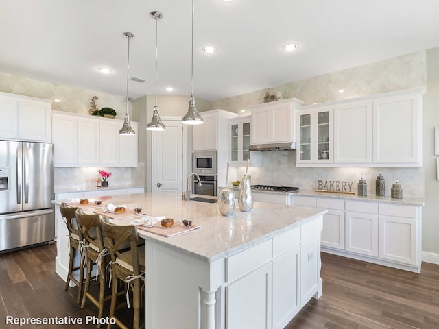 kitchen with dark hardwood / wood-style flooring, a kitchen island with sink, pendant lighting, and stainless steel appliances