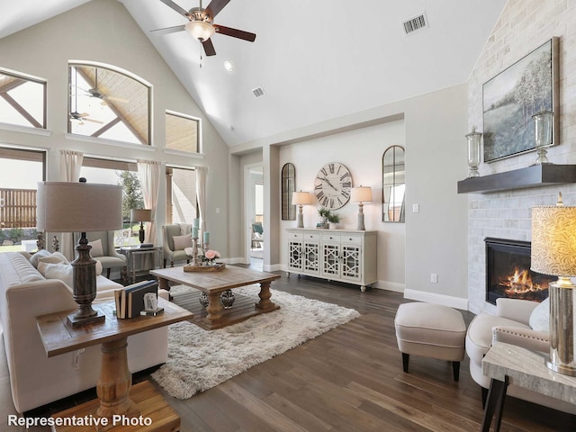 living room with ceiling fan, high vaulted ceiling, dark hardwood / wood-style floors, and a brick fireplace