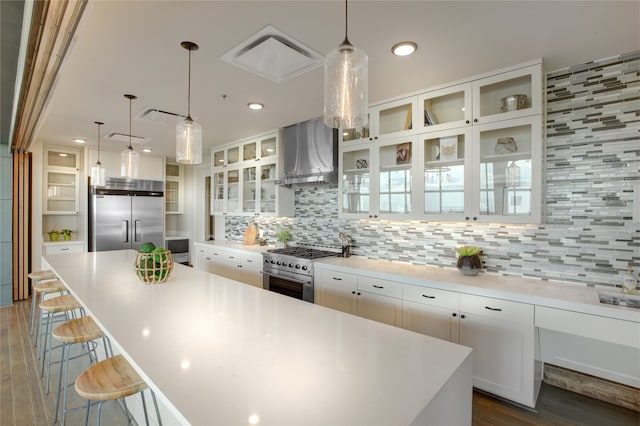 kitchen featuring decorative backsplash, exhaust hood, high quality appliances, a center island, and white cabinetry