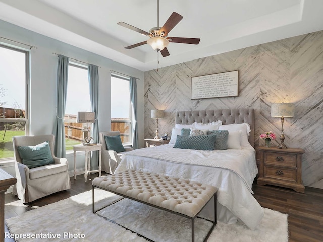 bedroom with a raised ceiling, ceiling fan, and dark hardwood / wood-style flooring