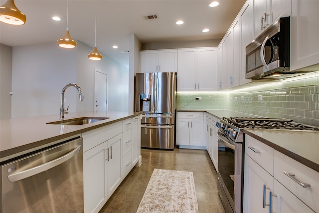 kitchen featuring pendant lighting, sink, tasteful backsplash, white cabinetry, and stainless steel appliances