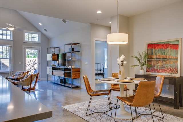 dining room with ceiling fan, high vaulted ceiling, and concrete flooring