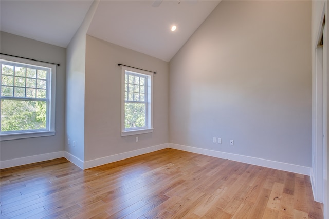 empty room with a wealth of natural light, high vaulted ceiling, and light wood-type flooring