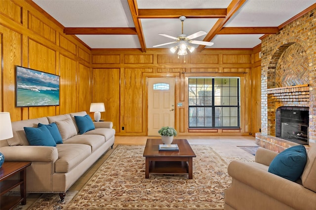 living room with coffered ceiling, wooden walls, ceiling fan, a fireplace, and beamed ceiling