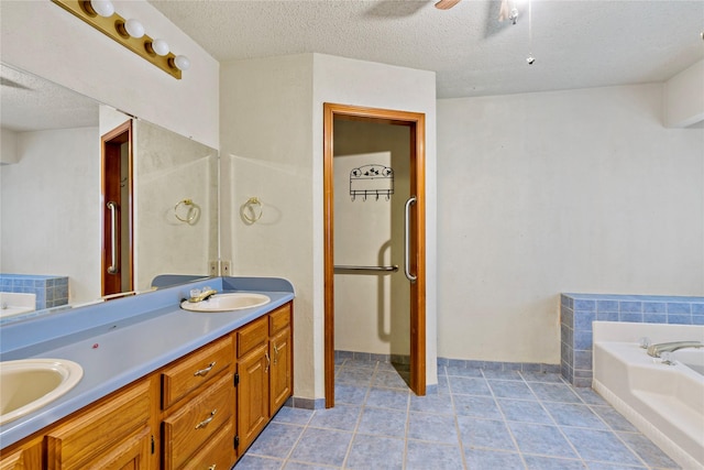 bathroom with vanity, a bath, a textured ceiling, and ceiling fan