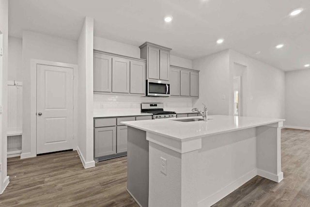 kitchen featuring a kitchen island with sink, sink, gray cabinets, and appliances with stainless steel finishes