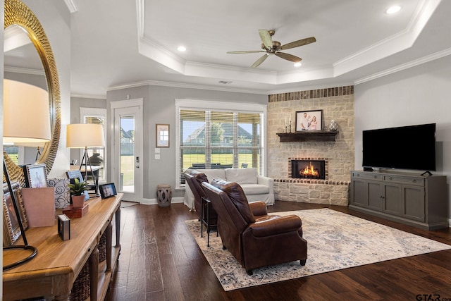 living room featuring dark hardwood / wood-style floors, a raised ceiling, plenty of natural light, and ornamental molding