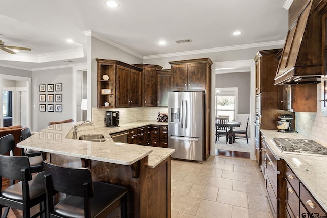 kitchen with sink, stainless steel appliances, kitchen peninsula, a breakfast bar, and ornamental molding