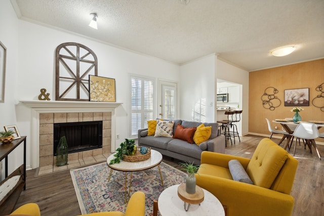 living room featuring a fireplace, ornamental molding, a textured ceiling, and hardwood / wood-style flooring