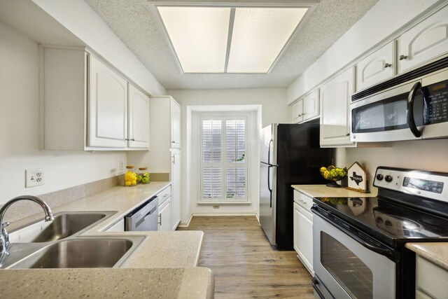 kitchen with white cabinetry, sink, light hardwood / wood-style floors, a textured ceiling, and appliances with stainless steel finishes