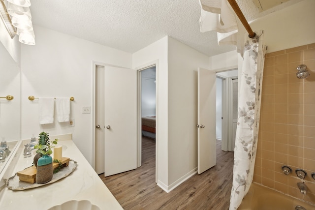 bathroom with a textured ceiling, vanity, wood-type flooring, and shower / bath combo