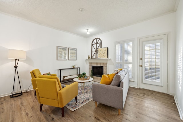 living room featuring a fireplace, a textured ceiling, light hardwood / wood-style flooring, and crown molding