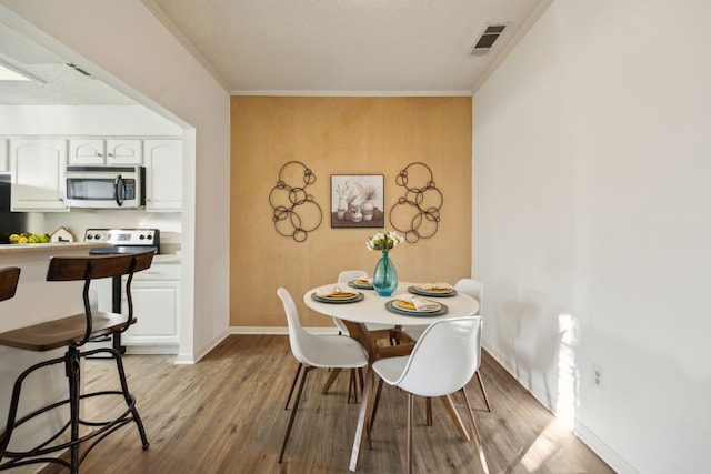 dining area featuring crown molding and light wood-type flooring