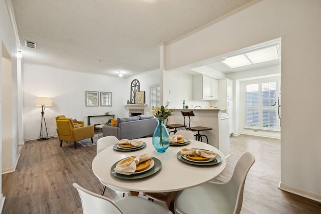 dining space with crown molding, a fireplace, hardwood / wood-style floors, and a textured ceiling