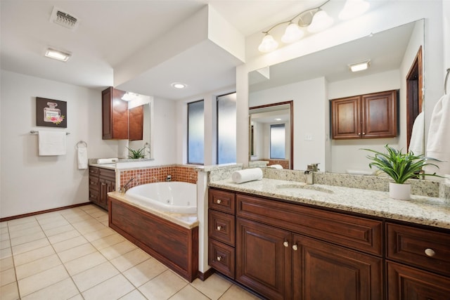 bathroom with tile patterned flooring, vanity, and tiled bath