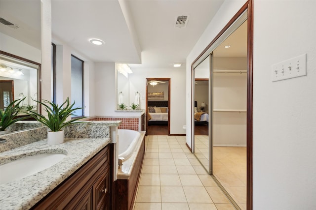 bathroom with tile patterned floors, tiled tub, and vanity