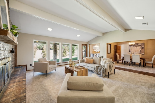 carpeted living room with a fireplace, vaulted ceiling with beams, and an inviting chandelier