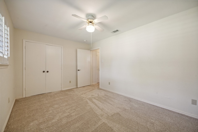 unfurnished bedroom featuring ceiling fan, a closet, and light colored carpet