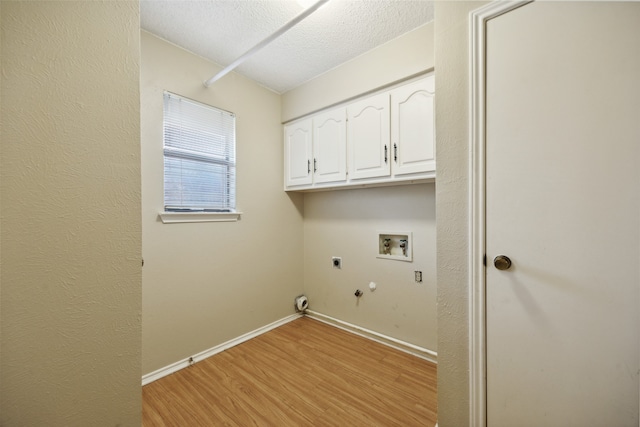 clothes washing area featuring cabinets, gas dryer hookup, hookup for a washing machine, light hardwood / wood-style flooring, and a textured ceiling