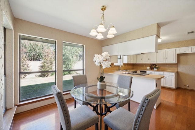 dining space with a notable chandelier, sink, and light hardwood / wood-style flooring