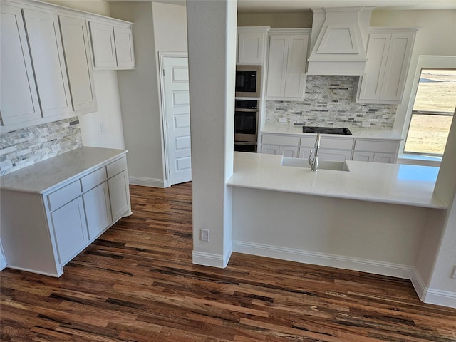 kitchen featuring stainless steel oven, custom range hood, and white cabinets