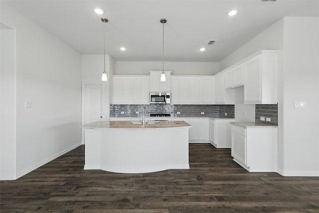 kitchen with dark wood-style floors, light stone counters, stainless steel microwave, and visible vents