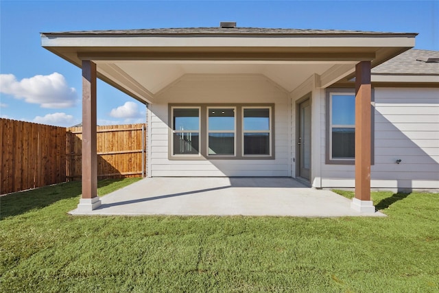 back of property with a yard, roof with shingles, a patio area, and fence