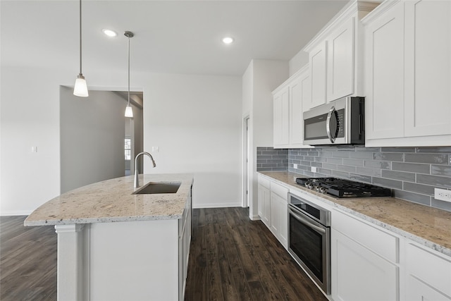 kitchen with appliances with stainless steel finishes, dark wood-type flooring, a sink, and tasteful backsplash