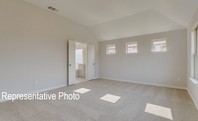 carpeted spare room featuring vaulted ceiling