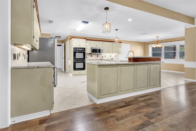 kitchen featuring a kitchen island, light stone counters, hanging light fixtures, and appliances with stainless steel finishes